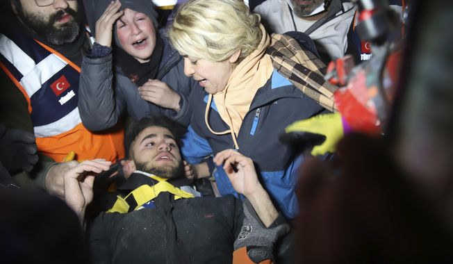 Rescuers and mother surround Adnan Mohammet Korkut after he was rescued in Gaziantep, southern Turkey, early Friday, Feb. 10, 2023. The teenager was pulled largely unscathed from beneath the rubble of a collapsed building in the Turkish city of Gaziantep early Friday, in a dramatic rescue that belied the reality that the chances of finding many more survivors four days after a catastrophic earthquake killed tens of thousands are shrinking fast. (IHA via AP)