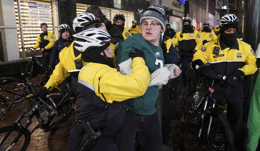 Police officers detain a Philadelphia Eagles supporter near a crowd reacting to the Super Bowl 57 NFL football game between the Kansas City Chiefs and the Eagles, Sunday, Feb. 12, 2023, in Philadelphia. The Chiefs won 38-35. (AP Photo/Nathan Howard)