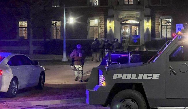 Armed police officers with weapons drawn rush into Phillips Hall on the campus of Michigan State University, in East Lansing, Mich., as authorities respond to reports of shootings, late Monday, Feb. 13, 2023. (Jakkar Aimery/Detroit News via AP)