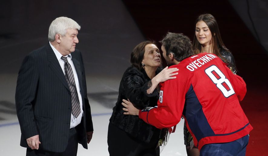 Mikhail Ovechkin, stands as his wife receives a kiss from their son, Washington Capitals left wing Alex Ovechkin, with his then-fiancé Nastya Shubskay, right, before he was presented a commemorative hockey stick by owner Ted Leonsis, Jan. 14, 2016, in Washington. Ovechkin says his father, Mikhail, has died. The Capitals captain delivered the news in Russian on his Instagram account. Ovechkin left the team yesterday to tend to a family health matter regarding a loved one. Coach Peter Laviolette said he expected Ovechkin to be gone for at least the rest of the week and away for the foreseeable future. (AP Photo/Alex Brandon, file)