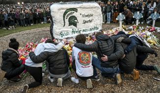 Friends of Brian Fraser gather around The Rock on the campus of Michigan State University, in East Lansing, Mich., on Wednesday, Feb. 15, 2023, during a vigil honoring MSU shooting victims Fraser, Arielle Anderson, Alexandria Verner and the five others injured. (Nick King/Lansing State Journal via AP)