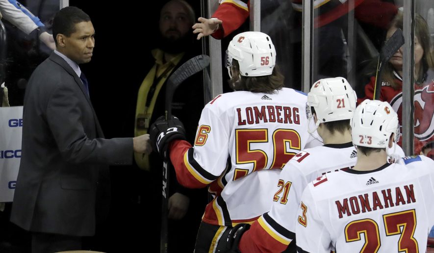Calgary Flames assistant coach Paul Jerrard, left, fist-bumps left wing Ryan Lomberg (56) as the team leaves the ice after defeating the New Jersey Devils in an NHL hockey game on Feb. 8, 2018, in Newark, N.J. Jerrard, one of the few Black assistant coaches in the NHL during his three stints in the league, died Wednesday, Feb. 15, 2023. He was 57. (AP Photo/Julio Cortez, File)