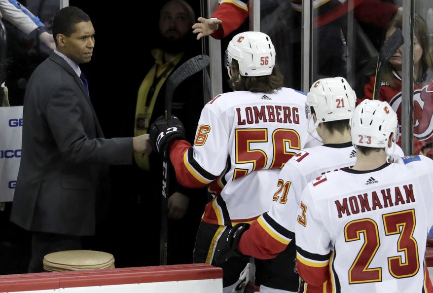 Calgary Flames assistant coach Paul Jerrard, left, fist-bumps left wing Ryan Lomberg (56) as the team leaves the ice after defeating the New Jersey Devils in an NHL hockey game on Feb. 8, 2018, in Newark, N.J. Jerrard, one of the few Black assistant coaches in the NHL during his three stints in the league, died Wednesday, Feb. 15, 2023. He was 57. (AP Photo/Julio Cortez, File)