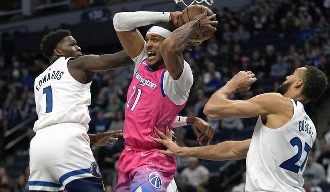 Washington Wizards center Daniel Gafford (21) looks to pass while defended by Minnesota Timberwolves guard Anthony Edwards (1), left, and center Rudy Gobert (27) during the first half of an NBA basketball game, Thursday, Feb. 16, 2023, in Minneapolis. (AP Photo/Abbie Parr)