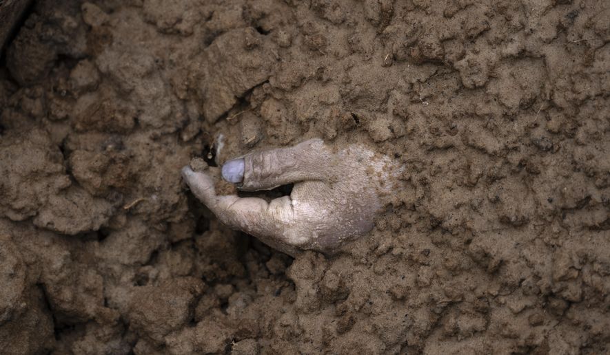 FALTA 13, 28 FILE - The hand of a corpse buried along with other bodies is seen in a mass grave in Bucha, in the outskirts of Kyiv, Ukraine, Sunday, April 3, 2022. (AP Photo/Rodrigo Abd, File)
