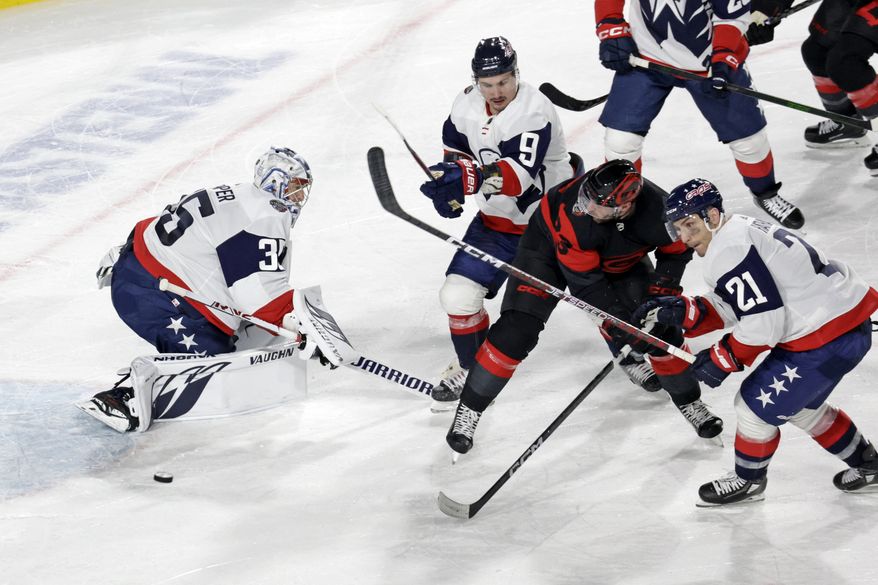 Carolina Hurricanes right wing Stefan Noesen (23) is defended by Washington Capitals goaltender Darcy Kuemper (35), defenseman Dmitry Orlov (9) and right wing Garnet Hathaway (21) during the third period of an NHL hockey Stadium Series game Saturday, Feb. 18, 2023, in Raleigh, N.C. (AP Photo/Chris Seward)