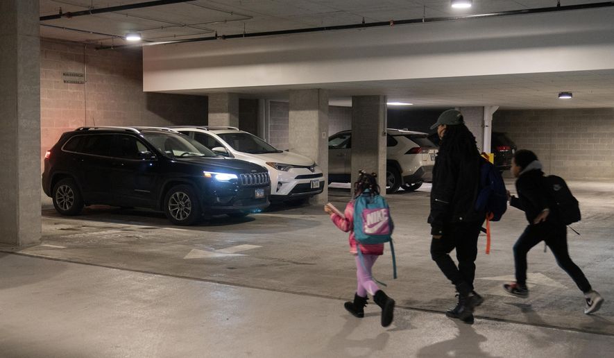 Johnae Strong, her 10-year-old son Akeim Smith and 6-year-old daughter Jari Akim rush to their car as they leave for school and work Friday, Feb. 10, 2023, in Chicago. Strong, a single mother of two, lost her partner and father to her daughter Jari, Malik Alim, when he drowned in in a boating accident while saving Jari and his son Ori in 2021. She said she usually spends over 40 hours per week doing clerical work for a small media company and as an independent filmmaker. &quot;Childcare is generally the biggest challenge,&quot; she said. (AP Photo/Erin Hooley)