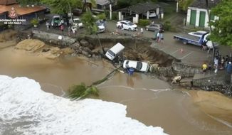 This photo provided by the Sao Paulo Government shows vehicles fallen from an elevated area along the beach in Sao Sebastiao, east of Sao Paulo, Brazil, Sunday, Feb. 19, 2023, after it was damaged by a severe weather system went through the area. (Sao Paulo Government via AP)