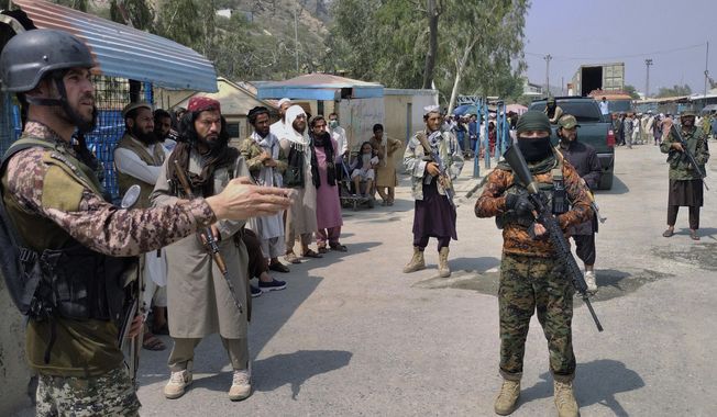 A Pakistani paramilitary soldier, left, and Taliban fighters stand guard on their respective sides, at a border crossing point between Pakistan and Afghanistan, in Torkham, in Khyber district, Pakistan, on Sept. 5, 2021. The Pakistani Taliban claimed responsibility for an attack in northwest Pakistan that left two soldiers and two militants dead. (AP Photo/Qazi Rauf, File)