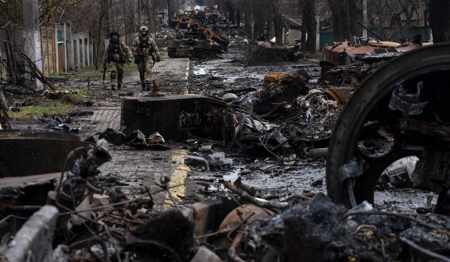 Soldiers walk amid destroyed Russian tanks in Bucha, in the outskirts of Kyiv, Ukraine, April 3, 2022. Eight months after Russian President Vladimir Putin launched an invasion against Ukraine expecting a lightning victory, the war continues, affecting not just Ukraine but also exacerbating death and tension in Russia among its own citizens. (AP Photo/Rodrigo Abd) **FILE**