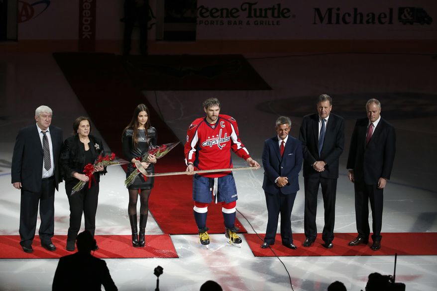 FILE - Mikhail Ovechkin, left, Tatyana Ovechkin, and fiancee Nastya Shubskay stand with Washington Capitals left wing Alex Ovechkin after he was presented a commemorative hockey stick by owner Ted Leonsis, president Dick Patrick, and general manager Brian MacLellan before an NHL hockey game against the Vancouver Canucks, Thursday, Jan. 14, 2016, in Washington. Ovechkin returned to the Washington Capitals on Wednesday after missing four games over the past week after the death of his father in Moscow. (AP Photo/Alex Brandon)