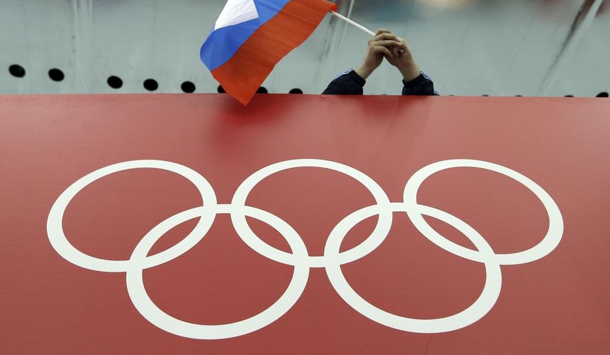 A Russian flag is held above the Olympic Rings at Adler Arena Skating Center during the Winter Olympics in Sochi, Russia on Feb. 18, 2014. Russia and its ally Belarus have been invited to compete at the Asian Games in the next step to qualify athletes for next year&#x27;s Paris Olympics. One year after the invasion of Ukraine began, Russia&#x27;s reintegration into the world of sports threatens to create the biggest rift in the Olympic movement since the Cold War. (AP Photo/David J. Phillip, File) **FILE**