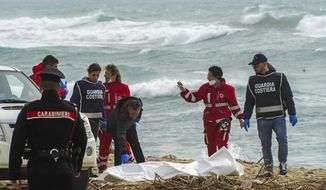 Italian Red Cross volunteers and coast guards recover a body after a migrant boat broke apart in rough seas, at a beach near Cutro, southern Italy, Sunday, Feb. 26, 2023. Rescue officials say an undetermined number of migrants have died and dozens have been rescued after their boat broke apart off southern Italy.(Antonino Durso/LaPresse via AP)
