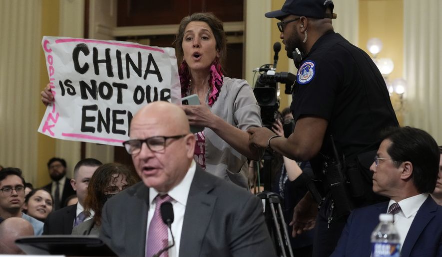 U.S. Capitol Police officers remove a protester as H.R. McMaster, former national security adviser to President Donald Trump, testifies during a hearing of a special House committee dedicated to countering China, on Capitol Hill, Tuesday, Feb. 28, 2023, in Washington. (AP Photo/Alex Brandon)
