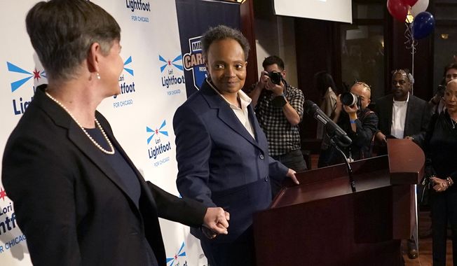 Chicago Mayor Lori Lightfoot, at podium, holds hands with her spouse, Amy Eshleman, as she concedes the election in the mayoral race, Tuesday, Feb. 28, 2023, in Chicago. (AP Photo/Charles Rex Arbogast)