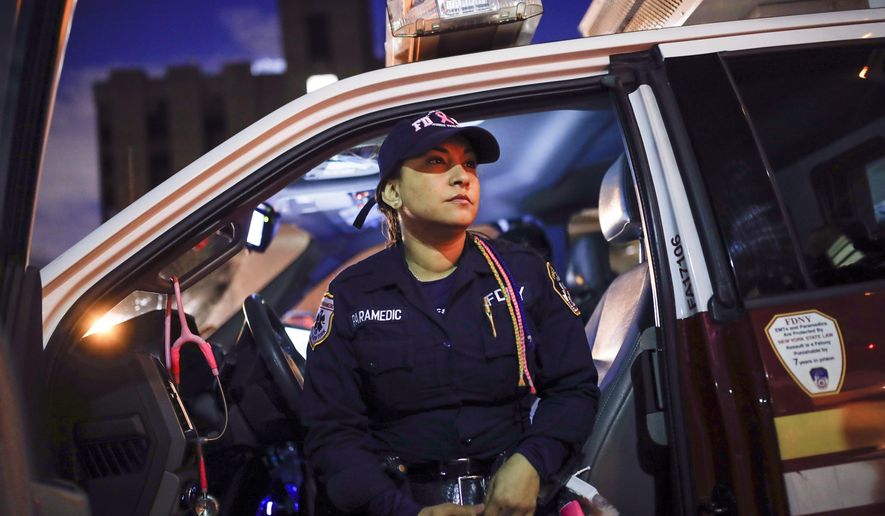 FILE — FDNY paramedic Elizabeth Bonilla wears her multicolored braids as she sits in her ambulance between calls after delivering a patient to Jacobi Medical Center, April 15, 2020, in the Bronx borough of New York. Four New York City ambulance workers, including Bonilla, who said they were disciplined for speaking to the media during the first harrowing months of the COVID-19 pandemic, have reached a settlement in their free speech lawsuit against the fire department and the city, their union announced Wednesday, March 1, 2023. (AP Photo/John Minchillo)