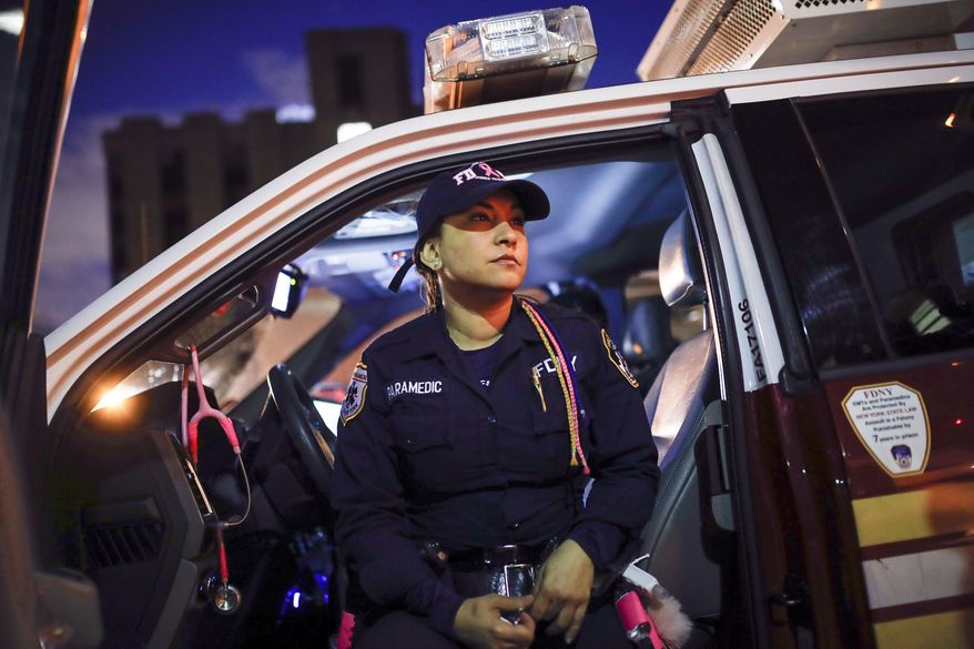 FILE — FDNY paramedic Elizabeth Bonilla wears her multicolored braids as she sits in her ambulance between calls after delivering a patient to Jacobi Medical Center, April 15, 2020, in the Bronx borough of New York. Four New York City ambulance workers, including Bonilla, who said they were disciplined for speaking to the media during the first harrowing months of the COVID-19 pandemic, have reached a settlement in their free speech lawsuit against the fire department and the city, their union announced Wednesday, March 1, 2023. (AP Photo/John Minchillo)