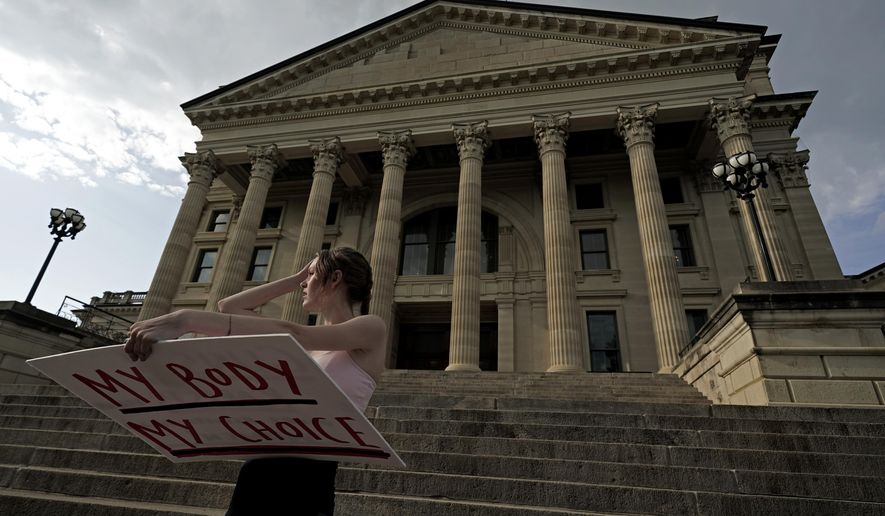 Zoe Schell, from Topeka, Kan., stands on the steps of the Kansas Statehouse during a rally to protest the Supreme Court&#x27;s ruling on abortion, June 24, 2022, in Topeka. Seven months after a decisive statewide vote affirmed abortion rights in Kansas, the Republican-controlled Legislature’s annual session in some ways looks a lot like previous ones, with multiple anti-abortion proposals. (AP Photo/Charlie Riedel) **FILE**