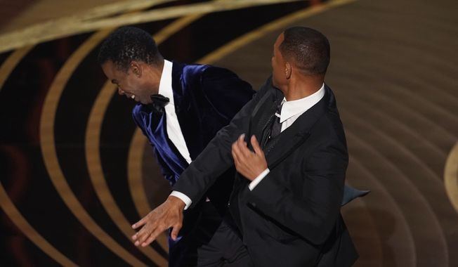 Will Smith, right, hits presenter Chris Rock on stage while presenting the award for best documentary feature at the Oscars on Sunday, March 27, 2022, at the Dolby Theatre in Los Angeles. Rock was the first artist to perform on Netflix&#x27;s first-ever live, global streaming event. (AP Photo/Chris Pizzello, File)