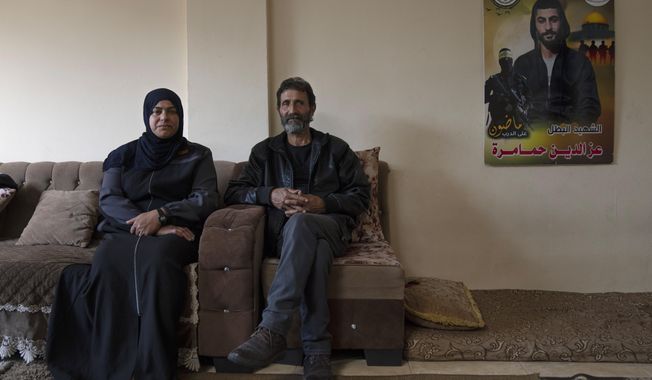 Bassem, 55, right and Lamia, 47, the parents of Palestinian militant Ezzeddin Hamamrah, 24, who was killed during an Israeli army raid on Jan. 14th, 2023, pose next to a poster with their son&#x27;s name and picture, at the family house in the West Bank village of Jaba, near Jenin, Tuesday, Feb. 28, 2023. The words on the picture read, &quot;The Martyr hero, we will keep the track&quot;. Across the West Bank, small independent groups of disillusioned young Palestinians are taking up guns against Israel&#x27;s open-ended occupation, defying Palestinian political leaders that they disdain as Israeli collaborators. (AP Photo/Nasser Nasser)