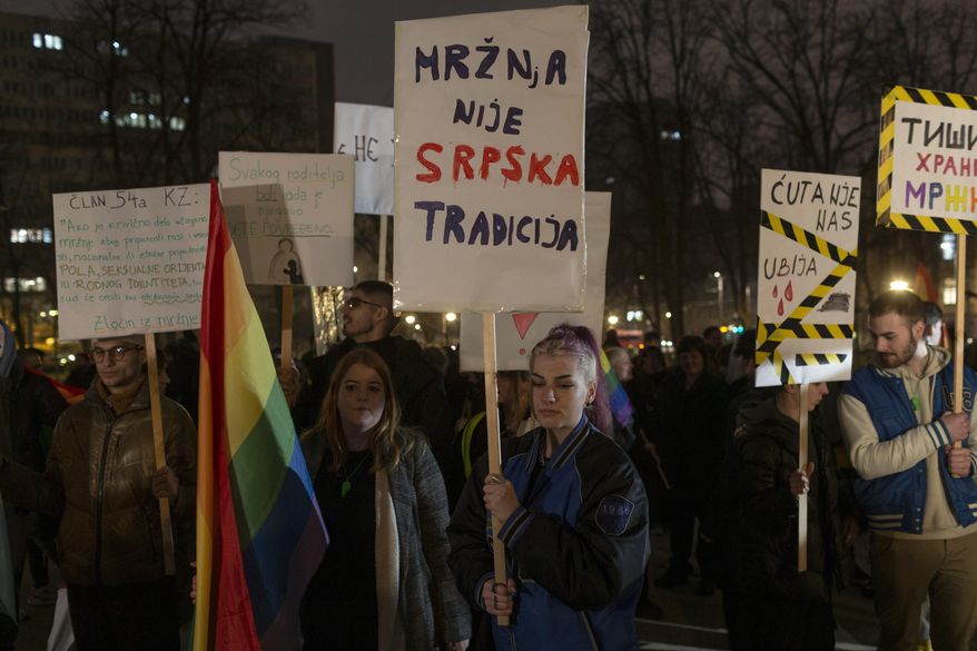 People hold banners as they attend a LGBTQ rights protest in central in Belgrade, Serbia, Friday, March 3, 2023. Local LGBTQ rights activists organized a protest after a gay person was attacked and gravely injured in the Serbian capital. Banner at center reads "Hate is not a Serbian tradition" in Serbian Latin letters. (AP Photo/Marko Drobnjakovic)