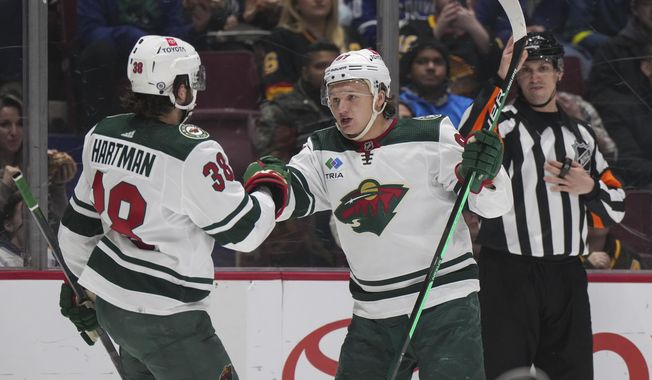 Minnesota Wild&#x27;s Kirill Kaprizov (97) celebrates his second goal against the Vancouver Canucks with Ryan Hartman (38), during the second period of an NHL hockey game Thursday, March 2, 2023, in Vancouver, British Columbia. (Darryl Dyck/The Canadian Press via AP)