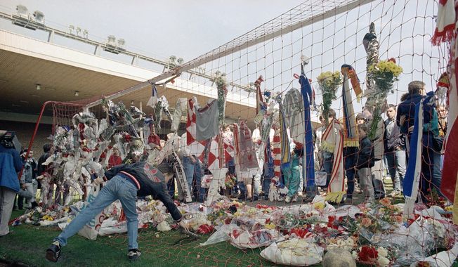 In this file photo dated April 16, 1989, a Liverpool Football Club fan places a pair of football boots in the goal at the Kop end of Anfield Stadium as hundreds came to mourn the loss of fellow Liverpool fans. Liverpool and Manchester United have jointly called on fans to end “tragedy chanting” ahead of their Premier League match on Sunday, March 5, 2023 at Anfield. The longtime rivals issued a statement Saturday from Liverpool manager Jurgen Klopp and United counterpart Erik ten Hag calling for an end to chants about tragedies such as Munich and Hillsborough. (AP Photo/Peter Kemp, File)