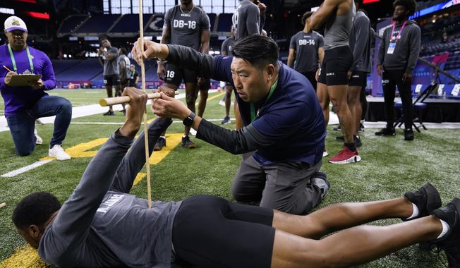 Denver Broncos scout Sae Woon Jo measures the flexiblity of Ball State defensive back Nic Jones at the NFL football scouting combine Friday, March 3, 2023, in Indianapolis. (AP Photo Erin Hooley)