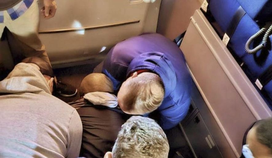 This image provided by Simik Ghookasian shows passengers and crew members restraining a man who according to federal authorities tried to open an airliner’s emergency door and tried to stab a flight attendant on a weekend flight from Los Angeles to Boston on Sunday, March 5, 2023. Simik Ghookasian, a passenger, said in a telephone interview that he was seated several rows behind the suspect, identified by federal authorities as Francisco Severo Torres, when he heard a commotion. (Simik Ghookasian via AP)