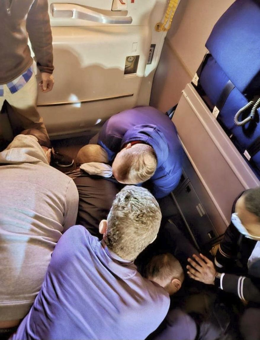 This image provided by Simik Ghookasian shows passengers and crew members restraining a man who according to federal authorities tried to open an airliner’s emergency door and tried to stab a flight attendant on a weekend flight from Los Angeles to Boston on Sunday, March 5, 2023. Simik Ghookasian, a passenger, said in a telephone interview that he was seated several rows behind the suspect, identified by federal authorities as Francisco Severo Torres, when he heard a commotion. (Simik Ghookasian via AP)