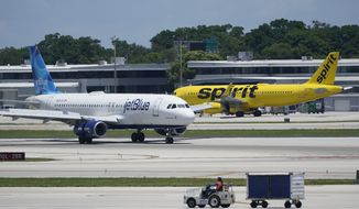 A JetBlue Airways Airbus A320, left, passes a Spirit Airlines Airbus A320 as it taxis on the runway, July 7, 2022, at the Fort Lauderdale-Hollywood International Airport in Fort Lauderdale, Fla. The Biden administration wants to block JetBlue from buying Spirit Airlines, saying the deal would reduce competition and hurt travelers. (AP Photo/Wilfredo Lee, File)