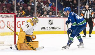 Vancouver Canucks&#x27; Elias Pettersson, right, scores on Nashville Predators goalie Juuse Saros during the shootout in an NHL hockey game in Vancouver, British Columbia, Monday, March 6, 2023. The Canucks defeated the Predators 4-3. (Rich Lam/The Canadian Press via AP)