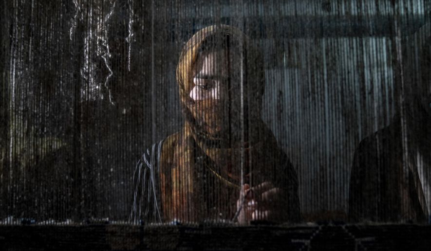 An Afghan woman weaves a carpet at a traditional carpet factory in Kabul, Afghanistan, Monday, March 6, 2023. After the Taliban came to power in Afghanistan, women have been deprived of many of their basic rights. (AP Photo/Ebrahim Noroozi)