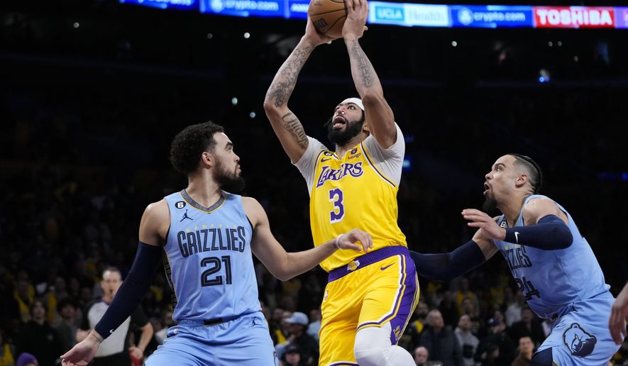 Los Angeles Lakers&#x27; Anthony Davis (3) goes up for a basket past Memphis Grizzlies&#x27; Tyus Jones (21) and Dillon Brooks (24) during the first half of an NBA basketball game Tuesday, March 7, 2023, in Los Angeles. (AP Photo/Jae C. Hong)