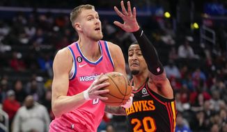 Washington Wizards center Kristaps Porzingis, left, looks to pass in front of Atlanta Hawks forward John Collins during the first half of an NBA basketball game Wednesday, March 8, 2023, in Washington. (AP Photo/Alex Brandon)