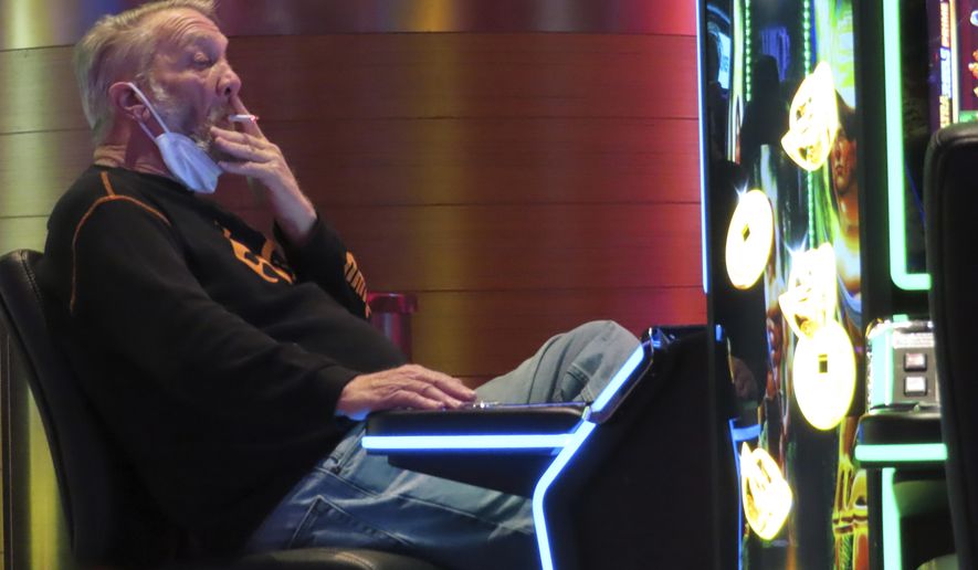 A gambler plays a slot machine while smoking in the Ocean Casino Resort in Atlantic City N.J. on Feb. 10, 2022. On Thursday, March 9, 2023, New Jersey legislators held a second hearing on a bill that would prohibit smoking at Atlantic City&#x27;s casinos, but again did not vote on it. (AP Photo/Wayne Parry)