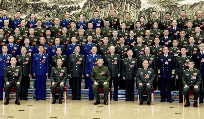 In this photo released by Xinhua News Agency, Chinese President Xi Jinping, bottom center, also general secretary of the Communist Party of China Central Committee and chairman of the Central Military Commission, poses for a group photo with deputies from the delegation of the People&#x27;s Liberation Army (PLA) and the People&#x27;s Armed Police Force before attending a plenary meeting of the delegation during the first session of the 14th National People&#x27;s Congress (NPC) in Beijing, on Wednesday, March 8, 2023. Xi has called for &quot;more quickly elevating the armed forces to world-class standards,&quot; in a speech coming days after he warned the country was threatened by a U.S.-led campaign of &quot;containment, encirclement and suppression of China.&quot; (Li Gang/Xinhua via AP)