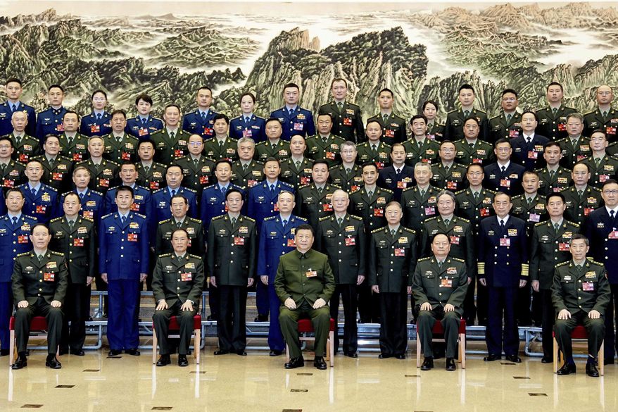 In this photo released by Xinhua News Agency, Chinese President Xi Jinping, bottom center, also general secretary of the Communist Party of China Central Committee and chairman of the Central Military Commission, poses for a group photo with deputies from the delegation of the People&#x27;s Liberation Army (PLA) and the People&#x27;s Armed Police Force before attending a plenary meeting of the delegation during the first session of the 14th National People&#x27;s Congress (NPC) in Beijing, on Wednesday, March 8, 2023. Xi has called for &quot;more quickly elevating the armed forces to world-class standards,&quot; in a speech coming days after he warned the country was threatened by a U.S.-led campaign of &quot;containment, encirclement and suppression of China.&quot; (Li Gang/Xinhua via AP)