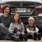 Peter Starostecki and his kids Sadie, center, and Jo Jo, pose behind their car with the vanity license plate that the state of Maine has deemed in appropriate, Wednesday, March 8, 2023, in Poland, Maine. The vegan family&#x27;s car will soon have a randomly selected plate. (AP Photo/Robert F. Bukaty)