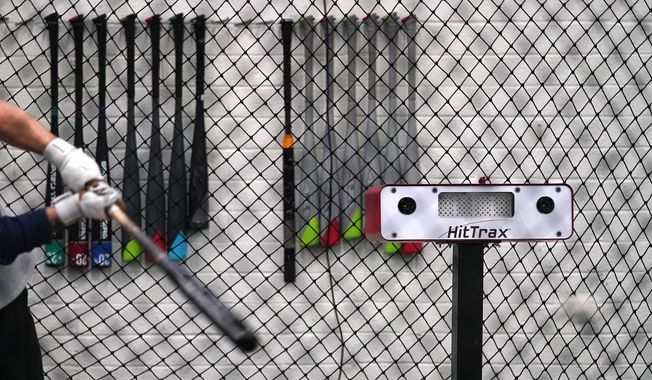 A batter takes a swing inside a batting cage as the swing data is computed by the device to the right of the batter at the Driveline facility in Scottsdale, Ariz., Thursday, Feb. 16, 2023. (AP Photo/Ross D. Franklin)