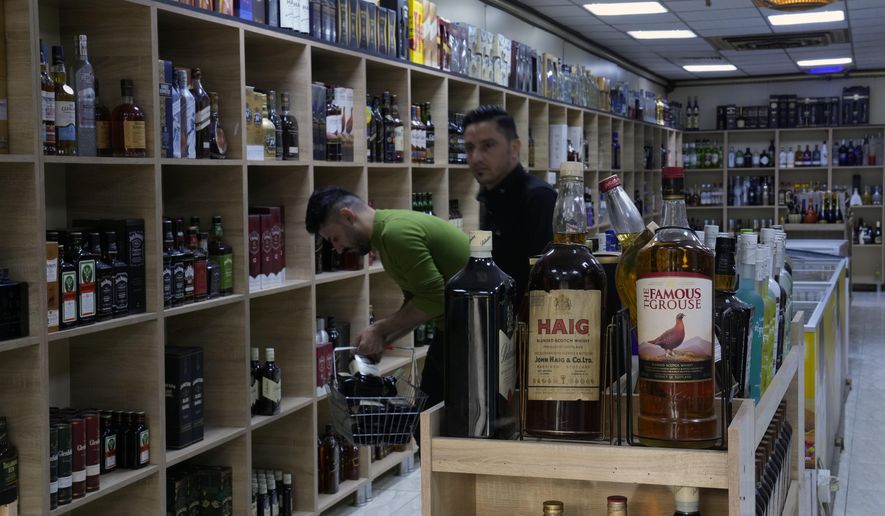 People buy alcohol in a liquor store in Baghdad, Iraq, Thursday, March 9, 2023. The Iraqi government started enforcing a 2016 ban on alcoholic beverages this month, although many liquor shops remained open in Baghdad. (AP Photo/Hadi Mizban)