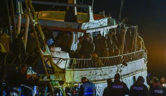 Police check a fishing boat with some 500 migrants in the southern Italian port of Crotone, early Saturday, March 11, 2023. The Italian coast guard was responding to three smugglers boats carrying more than 1,300 migrants “in danger” off Italy’s southern coast, officials said Friday. Three small coast guard boats were rescuing a boat with 500 migrants about 70 nautical miles off the Calabria region, which forms the toe of the Italian boot. (AP Photo/Valeria Ferraro)