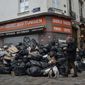 A man walks past piles of garbage in Paris, Monday, March 13, 2023. A contentious bill that would raise the retirement age in France from 62 to 64 got a push forward with the Senate&#x27;s adoption of the measure amid strikes, protests and uncollected garbage piling higher by the day. (AP Photo/Lewis Joly)