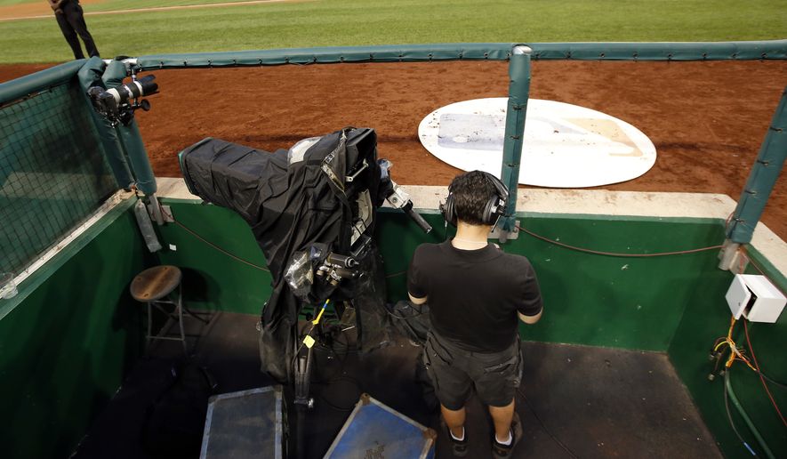 A MASN network videographer checks his phone after technical problems forced the network to use a different feed for several innings of a baseball game between the Washington Nationals and the Philadelphia Phillies at Nationals Park Saturday, Aug. 2, 2014, in Washington. (AP Photo/Alex Brandon) **FILE**