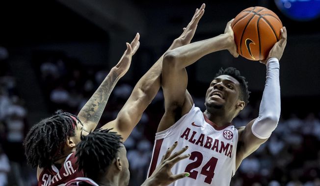 Alabama forward Brandon Miller (24) fires off a shot with Arkansas guard Nick Smith Jr. (3) and guard Davonte Davis (4) defending during the second half of an NCAA college basketball game, Saturday, Feb. 25, 2023, in Tuscaloosa, Ala. Miller was selected to the Associated Press All-America first team in results released Tuesday, March 14, 2023. (AP Photo/Vasha Hunt, File)