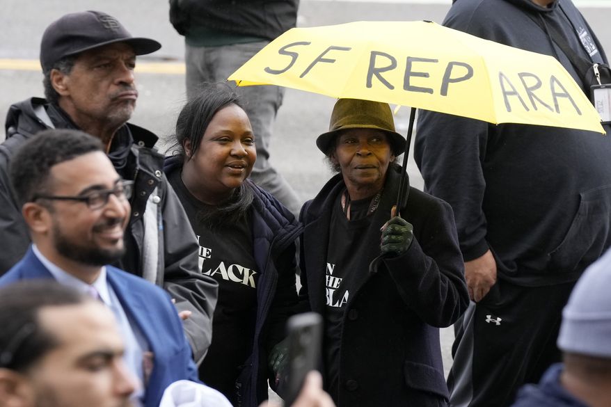 Pia Harris, with the San Francisco Housing Development Corporation, second from left, and her mother, Adrian Williams, listen to speakers at a reparations rally outside of City Hall in San Francisco, Tuesday, March 14, 2023. Supervisors in San Francisco are taking up a draft reparations proposal that includes a $5 million lump-sum payment for every eligible Black person. (AP Photo/Jeff Chiu)