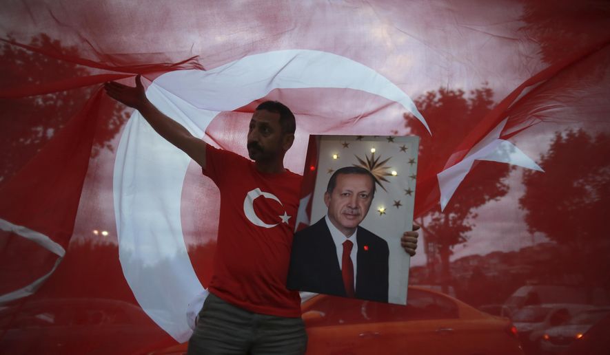 A man holds a picture of Turkey&#x27;s President and ruling Justice and Development Party, or AKP, leader Recep Tayyip Erdogan while celebrating outside the party headquarters in Istanbul, on June 24, 2018. (AP Photo/Emrah Gurel)