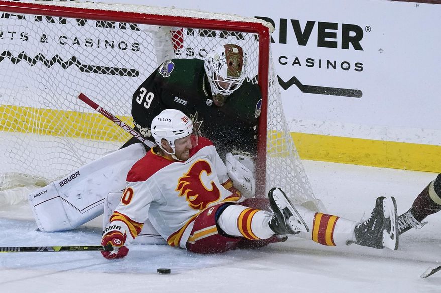 Calgary Flames&#x27; Blake Coleman (20) slides against Arizona Coyotes goalie Connor Ingram (39) during the second period of an NHL hockey game Tuesday, March 14, 2023, in Tempe, Ariz. (AP Photo/Darryl Webb)