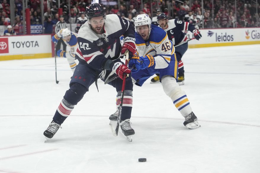 Washington Capitals right wing Tom Wilson (43) and Buffalo Sabres defenseman Ilya Lyubushkin (46) chase the puck in the first period of an NHL hockey game Wednesday, March 15, 2023, in Washington. (AP Photo/Carolyn Kaster)