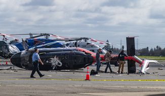 Officials inspect a crashed helicopter at Sacramento Executive Airport on Wednesday, March 15, 2023, in Sacramento, Calif. Authorities say the attempted theft of the helicopter ended in wreckage when it crashed at Sacramento Executive Airport. (Nathaniel Levine/The Sacramento Bee via AP)